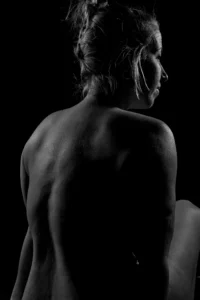 Profile in Shadow Black and white fine art photograph of a seated figure viewed from behind, with rim light defining the back, shoulder, and profile.