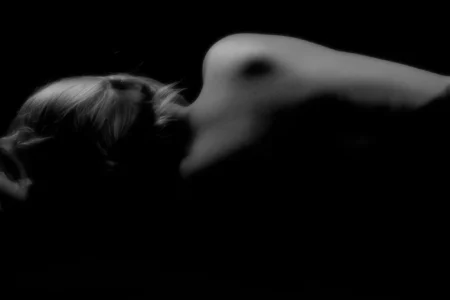 Reclining Form in Shadow Black and white fine art figure study of a reclining female form emerging from deep shadow.