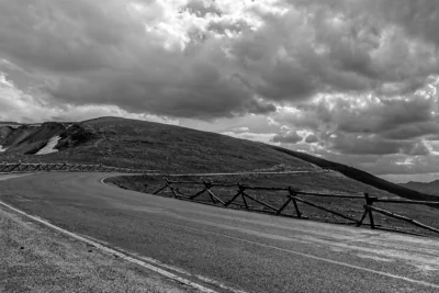 Trail Ridge Road, Rocky Mountain National Park, Colorado Black and white photograph of Trail Ridge Road curving through Rocky Mountain National Park beneath dramatic clouds.