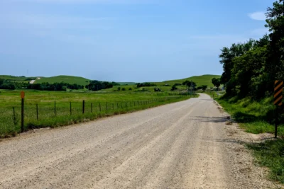 Deep Creek Road, Kansas Color photograph of Deep Creek Road in Kansas stretching through green prairie hills under a wide blue sky.