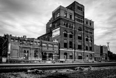The former Imperial Brewery building in Kansas City, photographed before its demolition. Black-and-white photograph of the former Imperial Brewery building in Kansas City beside railroad tracks.